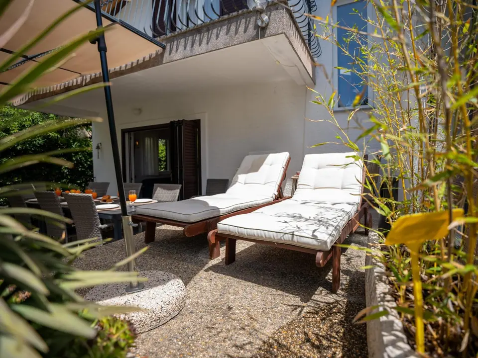 Sun loungers on the terrace beside a bamboo screen, dining table behind