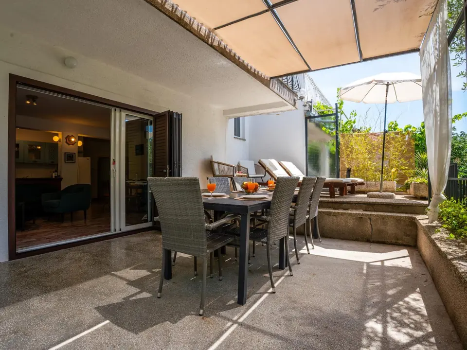 Covered terrace at Holiday Home Dolphin with a dining table for eight and open doors into the living room