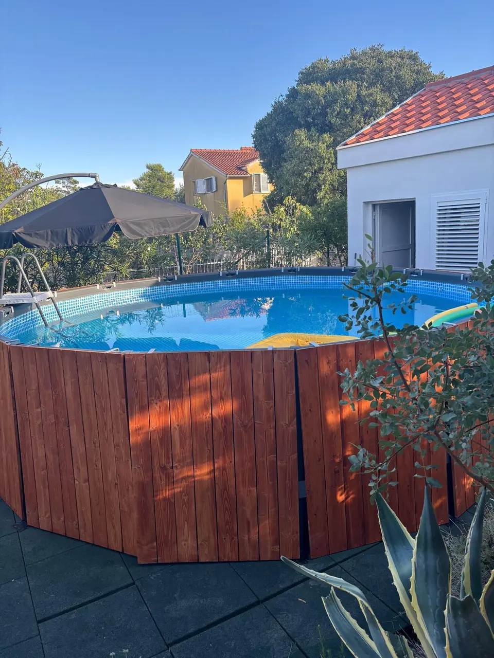 The private pool at Villa Marco Polo, wood-clad, with a parasol and steps
